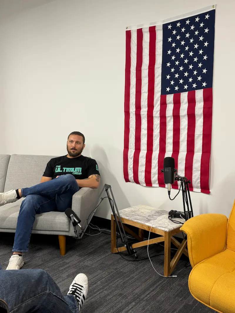 Jerrod from Ultimum Group recording in the Des Moines office with an American flag in the background.